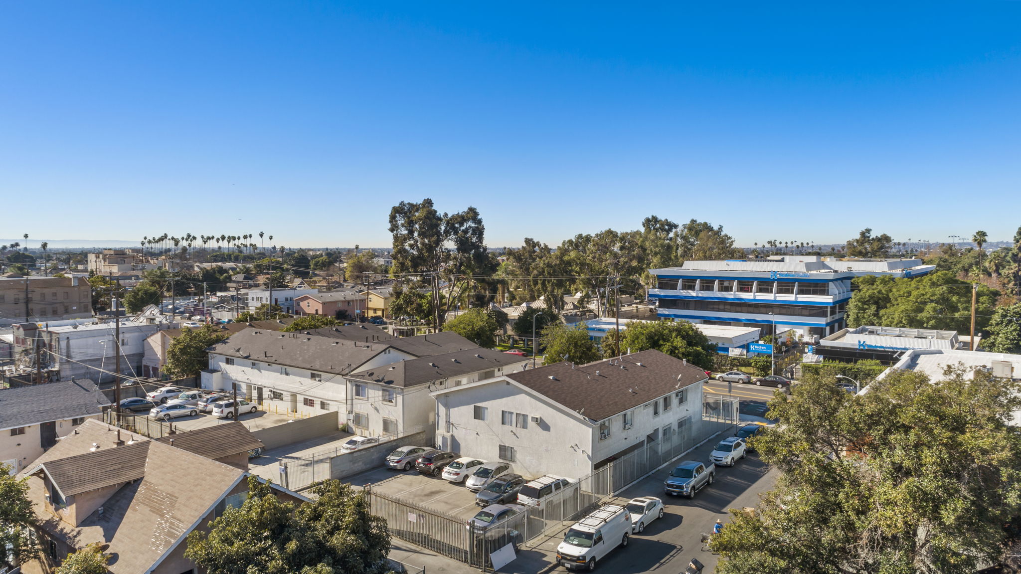 A clear blue sky over a residential area with houses and parked cars.
